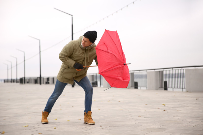 Un homme lutte contre le vent avec son parapluie rouge