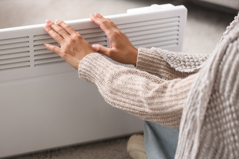 Une femme tend les mains vers un chauffage