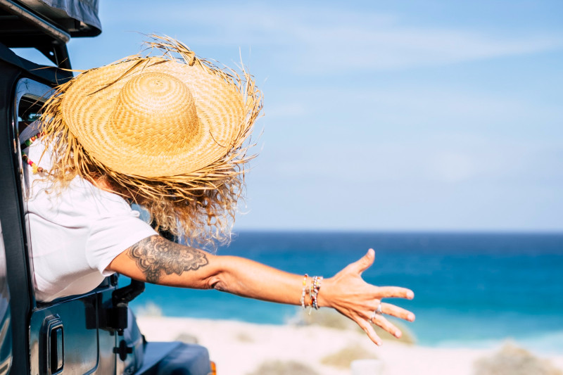 Une femme tend un bras face à la mer
