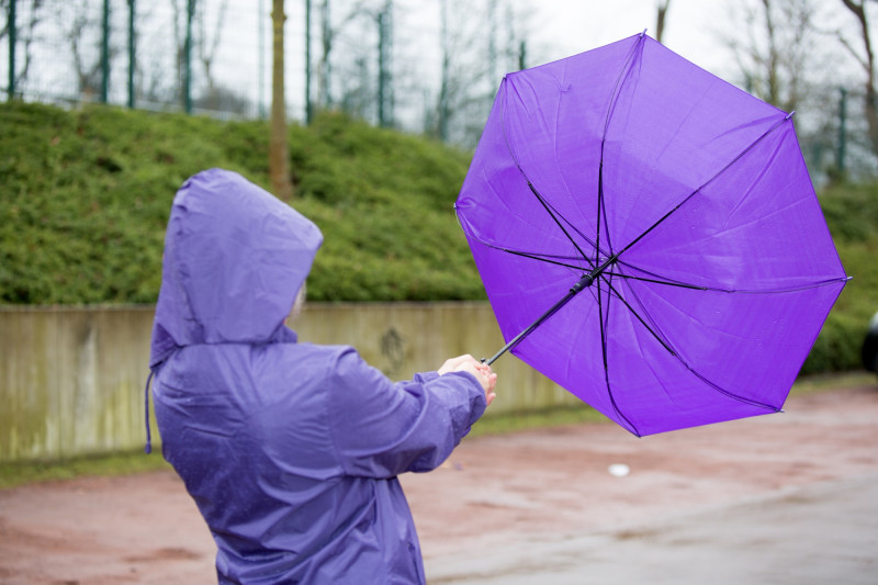 Une personne lutte contre le vent avec son parapluie