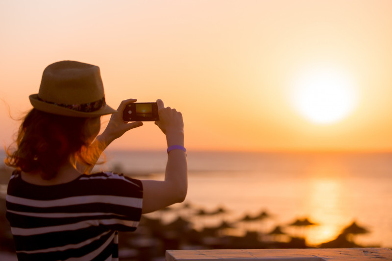 Une femme prend en photo le coucher de soleil