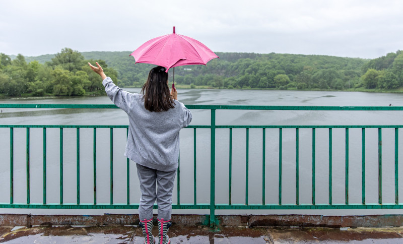 Une femme près d'un fleuve sous la pluie
