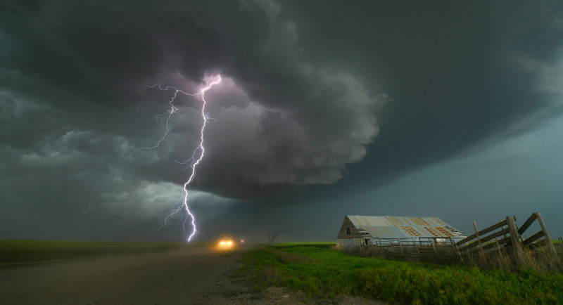 Lightning strikes near a road and farm building