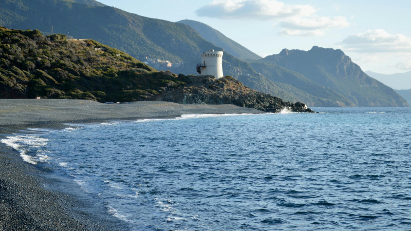 White tower on a rocky coast with the sea.