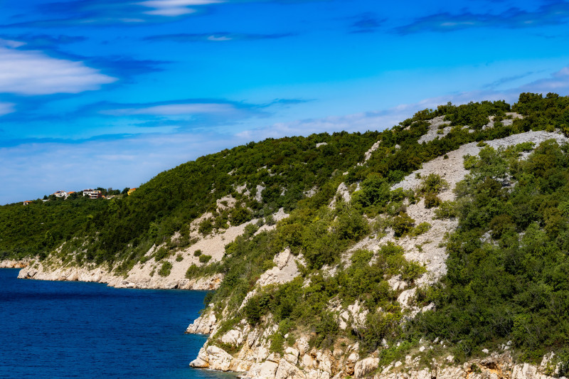 Capture d'une vue côtière époustouflante avec de riches collines verdoyantes et une mer bleue sous un ciel éclatant.