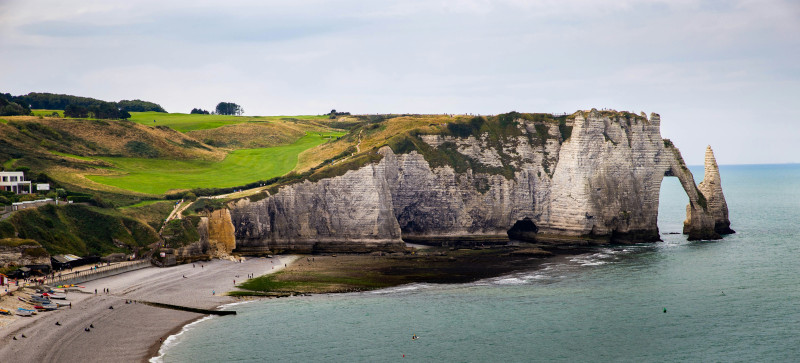 Coastal cliffs with a natural arch and green hills