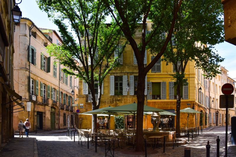 Coin de rue pittoresque à Aix-en-Provence, présentant une architecture traditionnelle et un café en plein air animé.