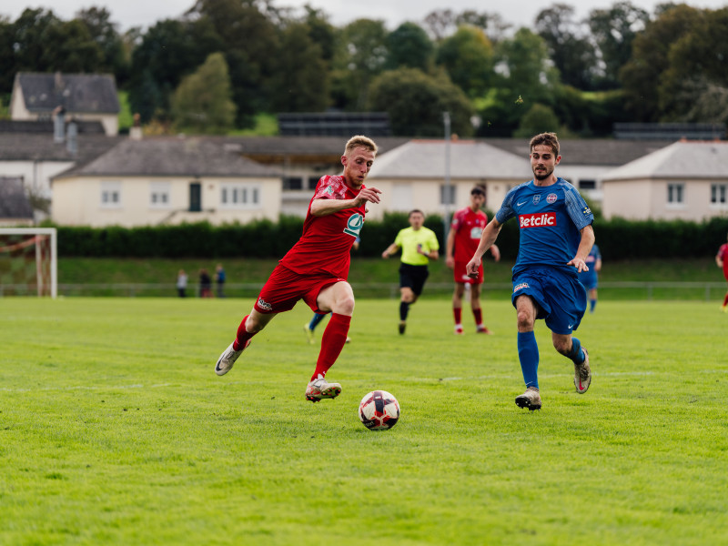 Photo d'action de joueurs de football en compétition sur un terrain verdoyant en plein air.