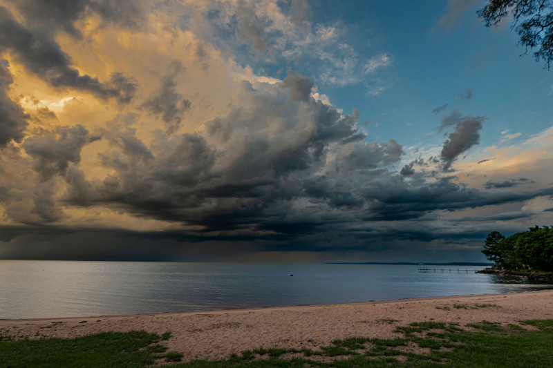 Superbe coucher de soleil sur la plage, avec des nuages ​​d'orage spectaculaires au-dessus de la mer tranquille.