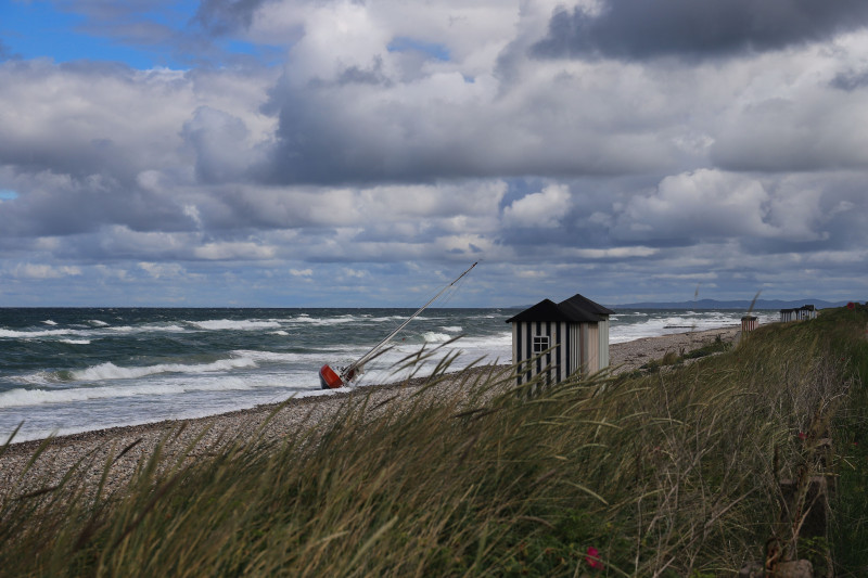 Vue spectaculaire d'un voilier échoué sur une plage danoise de la mer Baltique sous un ciel orageux.