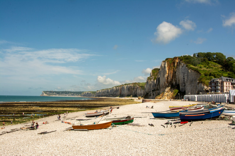 Vue panoramique de la plage d'Yport avec des bateaux de pêche et des falaises en Normandie, France.