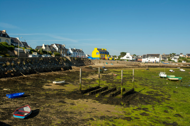 Charmant village balnéaire de Bretagne à marée basse, présentant une architecture colorée et des bateaux.