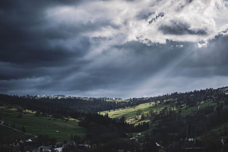 Paysage maussade de Biały Dunajec, en Pologne, avec des nuages spectaculaires et la lumière du soleil qui perce.