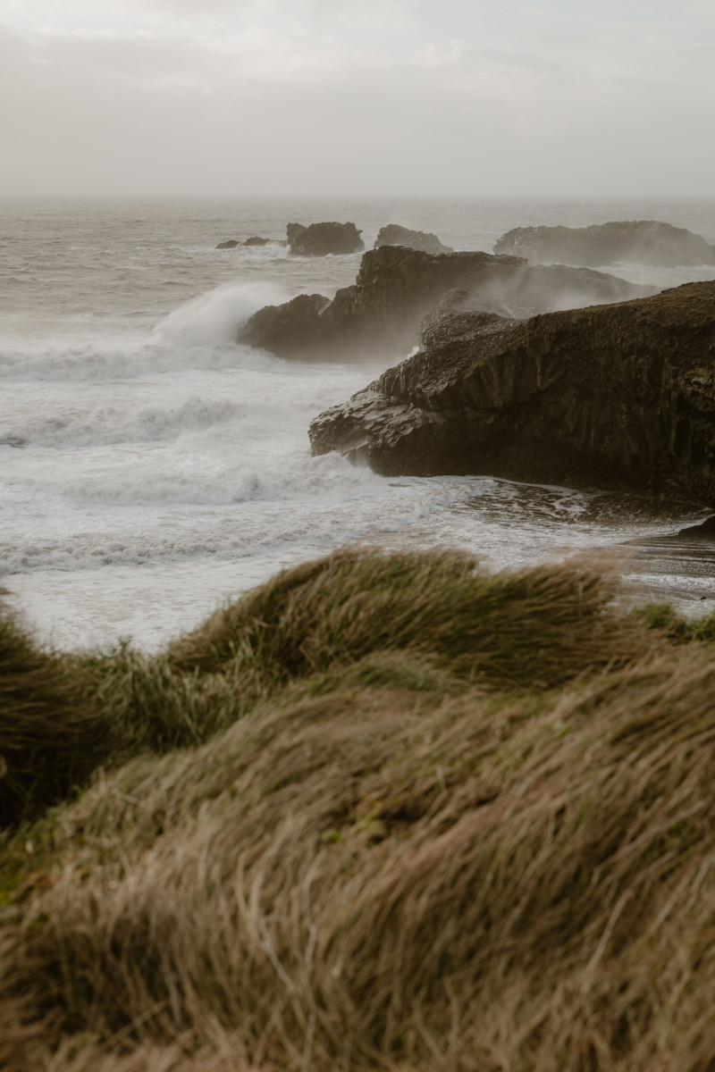 Scène spectaculaire de vagues océaniques s'écrasant contre des falaises rocheuses par temps couvert.