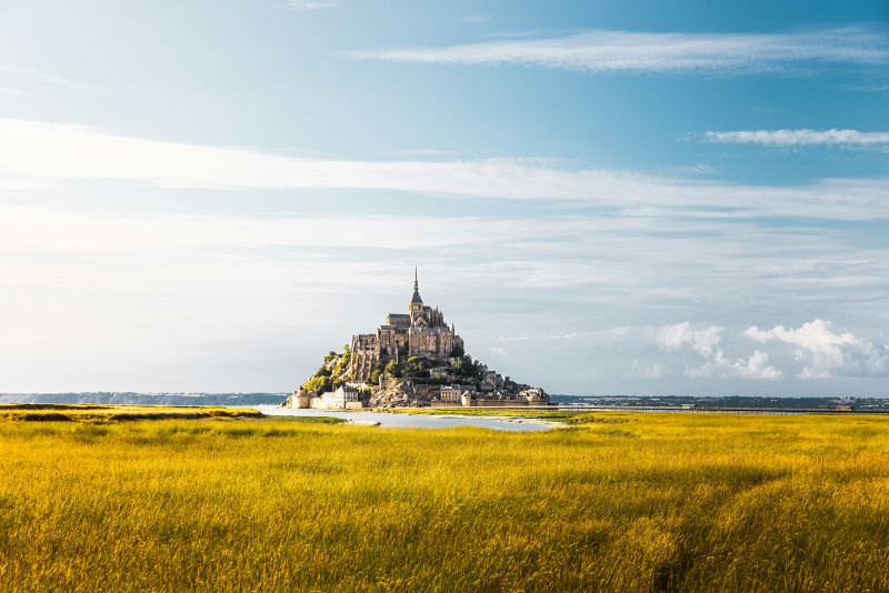 a castle on a hill with Mont Saint-Michel in the background