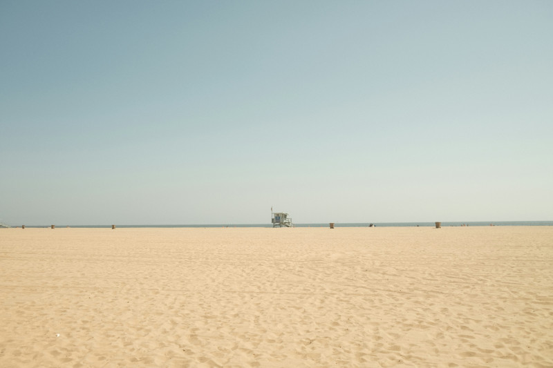a sandy beach with a lifeguard tower in the distance