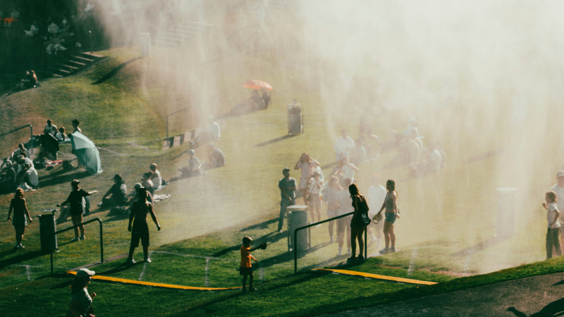 Crowds of people playing in water spray outdoors.