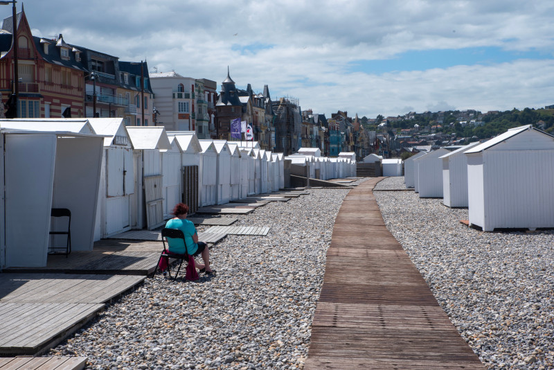 De charmantes cabanes de plage bordent la plage de galets de Mers-les-Bains, en France, par une journée ensoleillée.
