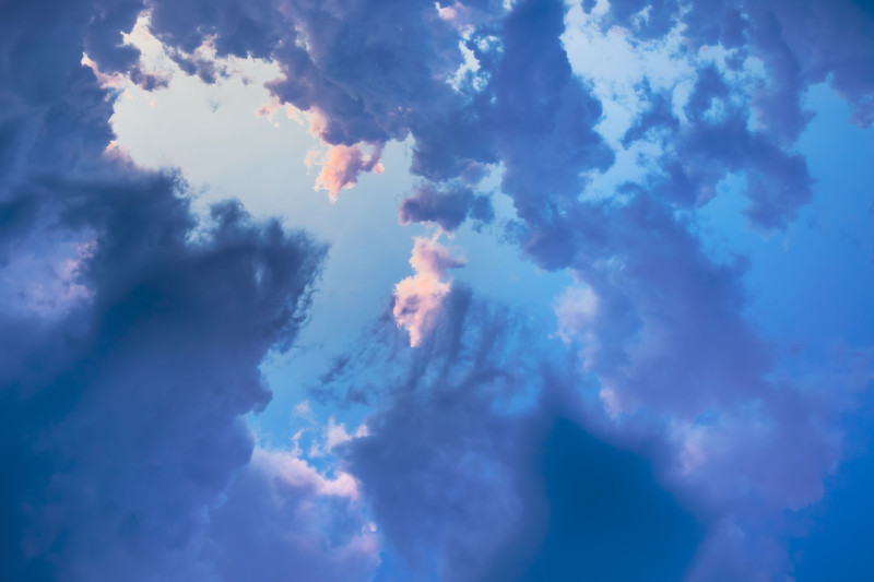 Des nuages dramatiques contre un ciel bleu vif, créant une atmosphère sereine et aérienne.
