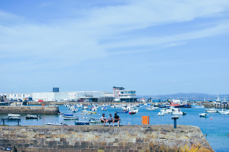 Une vue dynamique du port de Douarnenez en France avec des bateaux et des personnes profitant de la journée d'été.
