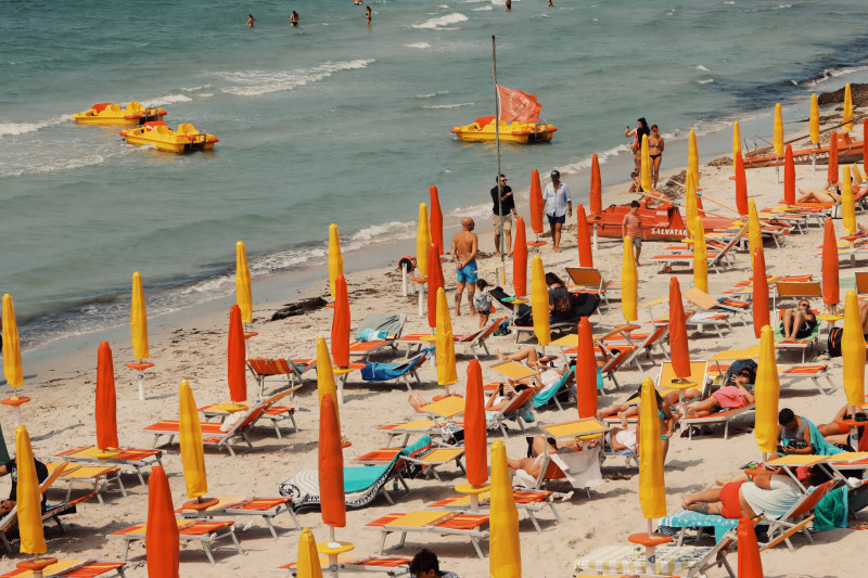 Plage vibrante de Sardaigne avec des parapluies colorés et des transats sous le soleil d'été.