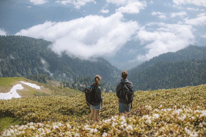 Deux randonneurs avec des sacs à dos admirent un magnifique paysage de montagne. Parfait pour des thèmes de voyage et d'aventure.