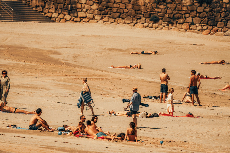 Des personnes se détendent et prennent le soleil sur une plage de sable en Espagne, profitant d'un jour d'été ensoleillé.