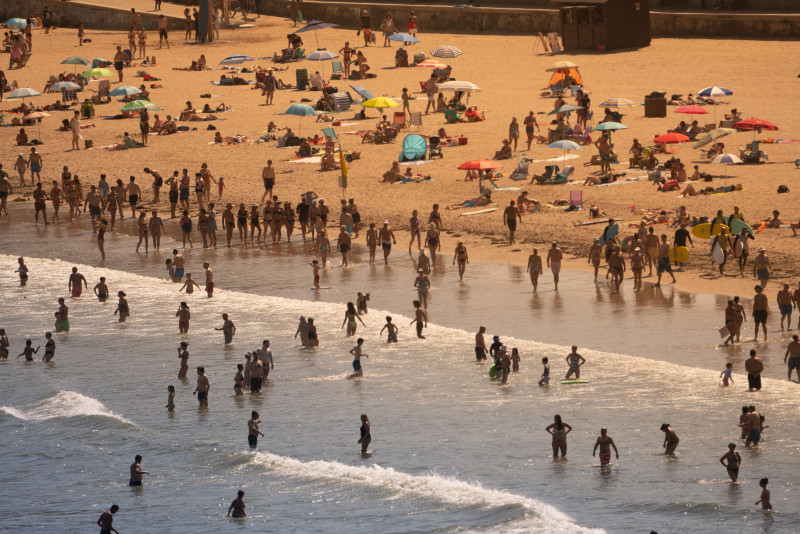 Vue aérienne d'une plage bondée avec des gens profitant d'une journée ensoleillée d'été.