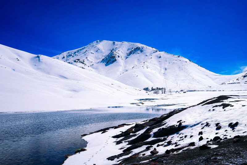 Vue hivernale à couper le souffle sur les montagnes enneigées et le lac serein d'Oukaïmeden, au Maroc.