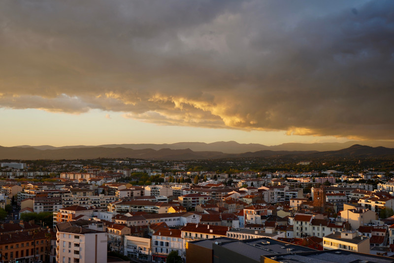 Un paysage urbain époustouflant sous un ciel de coucher de soleil spectaculaire avec des nuages pittoresques et des montagnes lointaines.