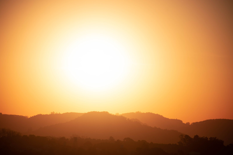 Silhouette de montagnes sous un coucher de soleil lumineux avec un ciel doré.