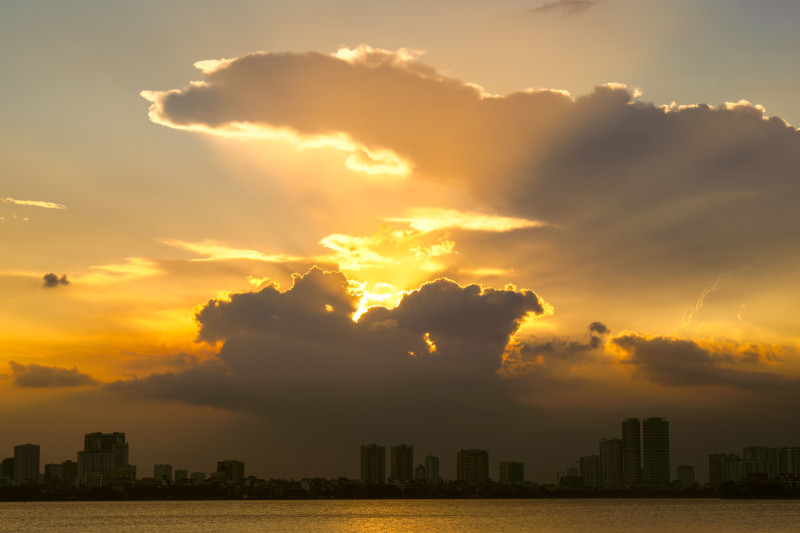 Coucher de soleil éblouissant sur la ligne d'horizon urbaine avec des nuages dramatiques et des teintes dorées.