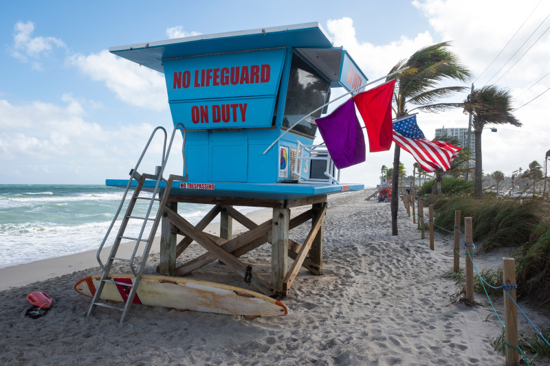 Une tour de sauveteur vibrante se dresse sur une plage de sable en Floride, États-Unis, avec des drapeaux flottant au vent.
