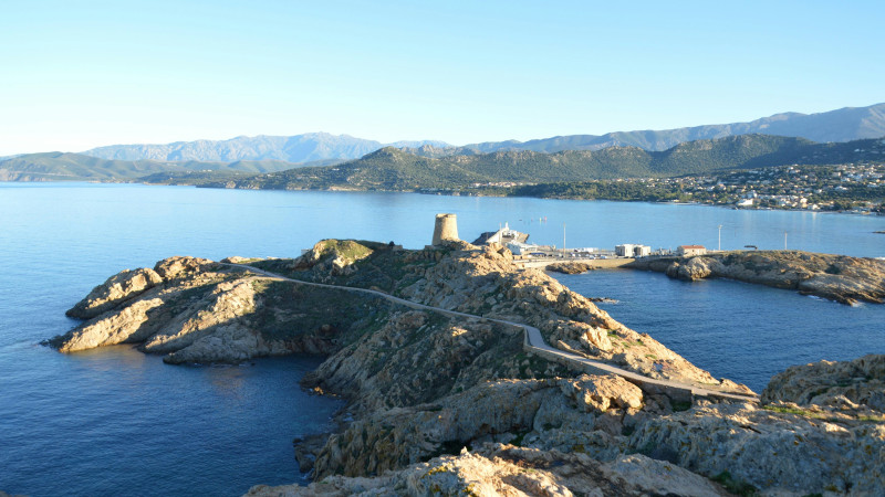 Rocky island with tower and harbor by the sea