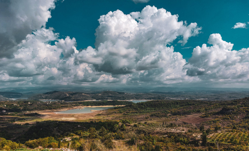 Vue à couper le souffle des collines ondulantes et de la rivière sous des nuages dramatiques, capturant la tranquillité rurale.
