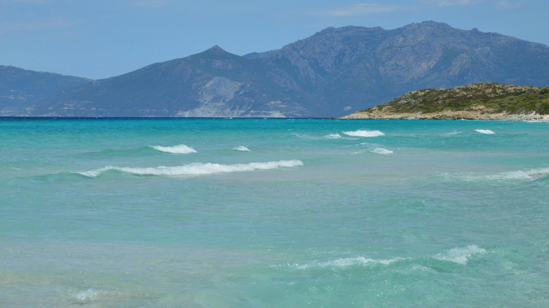 Turquoise ocean waves with distant mountains and a blue sky