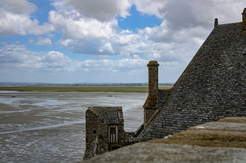 brown brick building near sea under blue sky and white clouds during daytime