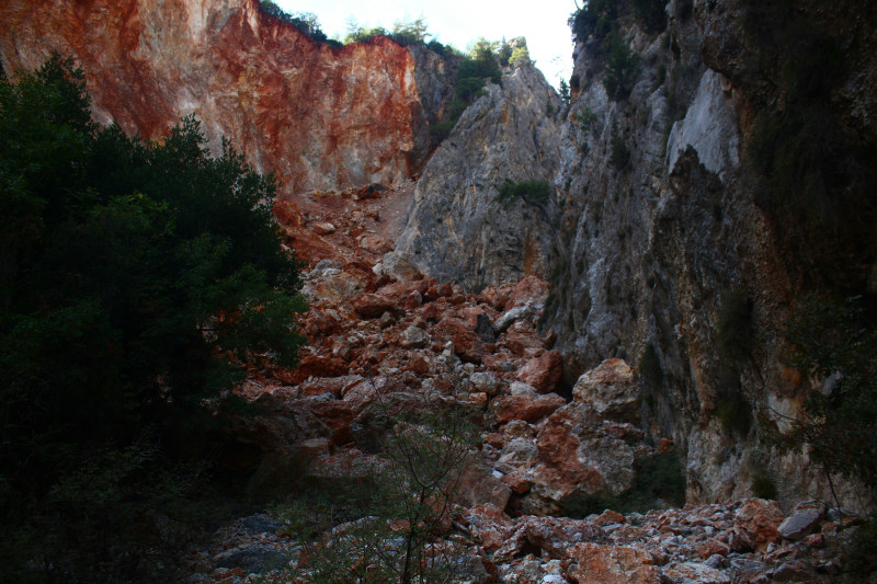 Rockslide in a quarry with red and gray cliffs