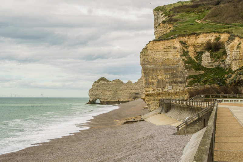 The cliffs of Etretat, Normandy, France. A view of a beach with a cliff in the background.