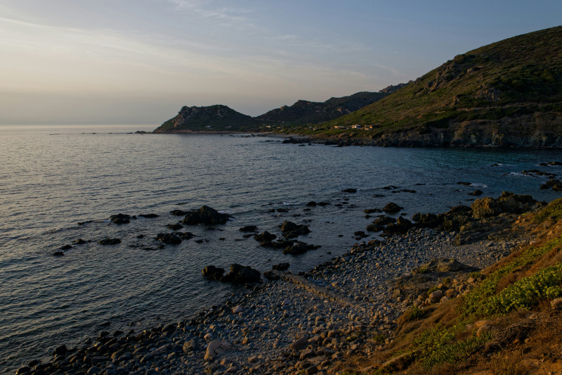 Rocky coastline with calm ocean and hills