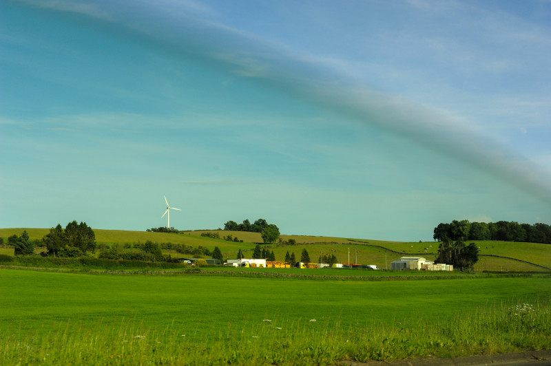 Green rolling hills with a wind turbine and farm buildings