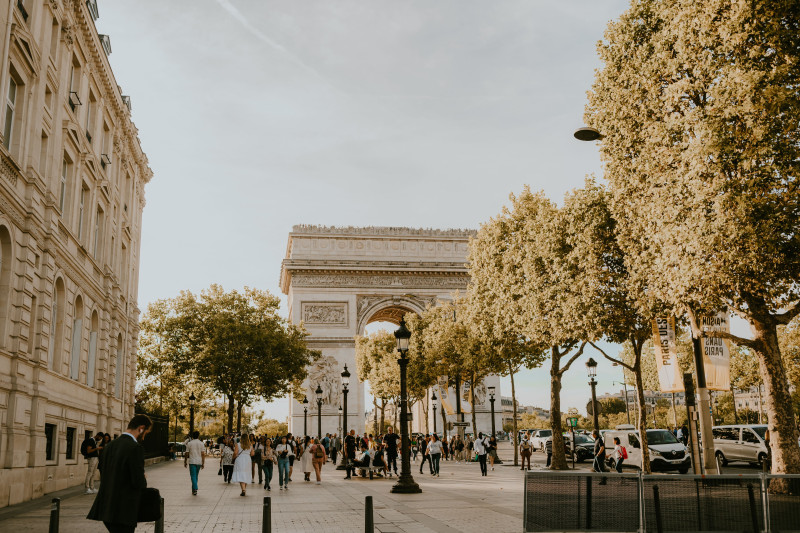 Vue charmante de l'emblématique Arc de Triomphe entouré de personnes profitant d'une belle soirée à Paris.