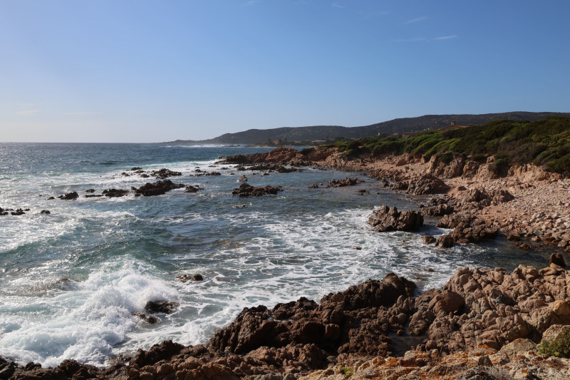 Vue pittoresque d'une côte rocheuse avec des vagues sous un ciel bleu limpide.