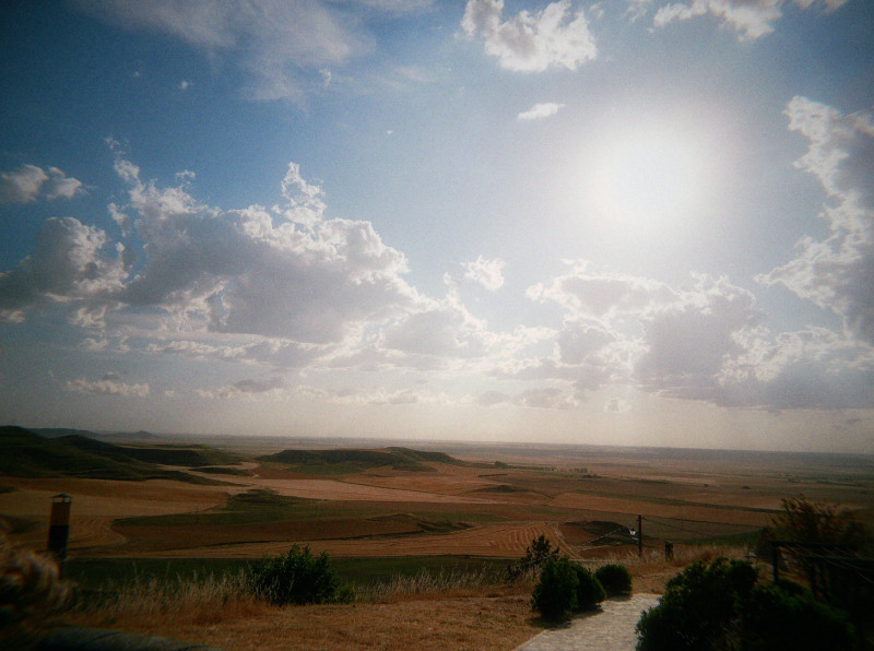Vast dry landscape under a bright sun and cloudy sky
