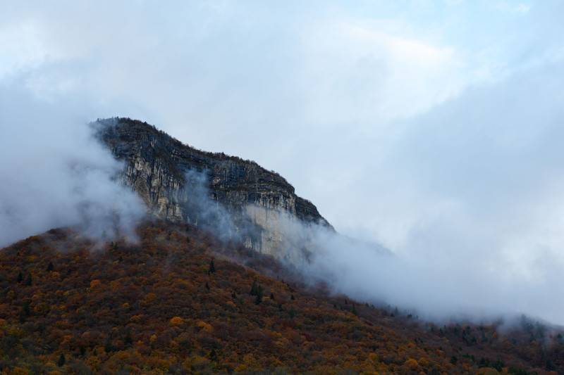 Un sommet montagneux brumeux entouré de feuillage automnal dans la région Auvergne-Rhône-Alpes, France.