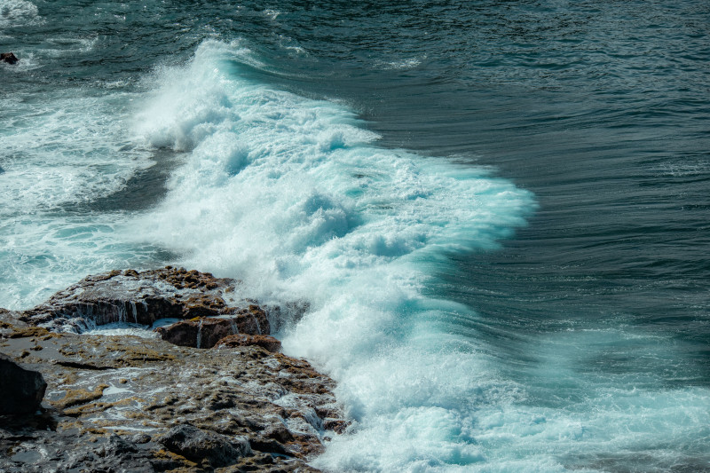 Des vagues dynamiques s'écrasent contre la côte rocheuse de Los Gigantes, Espagne, sous la lumière du jour, offrant une vue maritime parfaite.