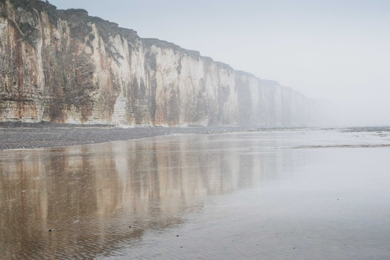 Paysage côtier éthéré avec des falaises imposantes et une ambiance brumeuse, parfait pour les amoureux de la nature.