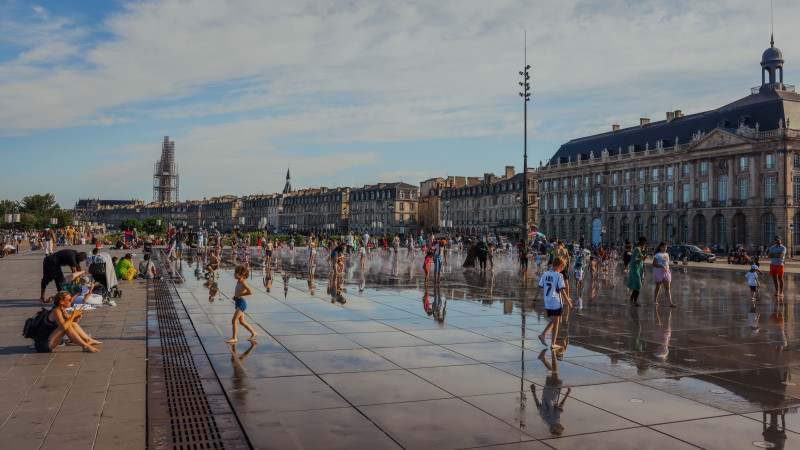 Scène animée à Bordeaux Place de la Bourse avec des familles profitant du bassin réfléchissant.