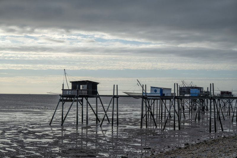 Pittoresques cabines de pêche sur pilotis à La Rochelle, France, capturant le paysage côtier serein au coucher du soleil.