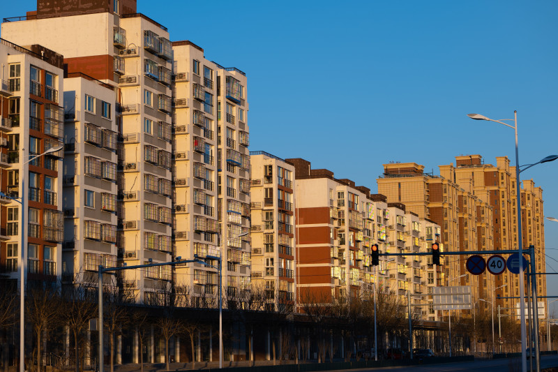 Une rangée de bâtiments d'appartements modernes éclairés par la lumière du coucher de soleil, mettant en valeur l'architecture urbaine.